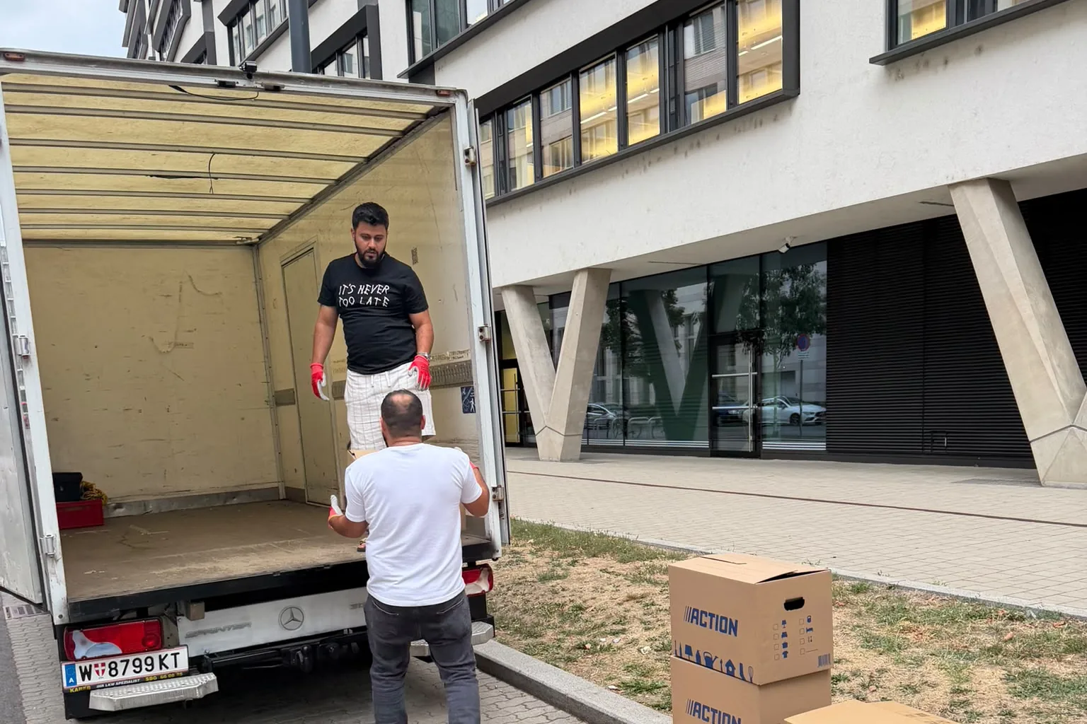 Zwei HAVEN-Mitarbeiter beladen den Sprinter vor einem Wiener Bürogebäude.